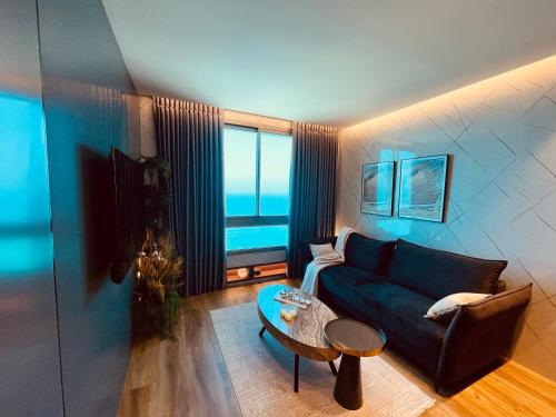 a living room with a blue couch and a table at C Tower Premium Apartments, Panoramic Sea View in Netanya