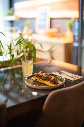 a plate of pizza on a table with a drink at Coloft in Lesquin
