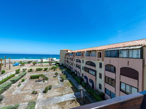an apartment building with the ocean in the background at Apartment Front de Mer-8 by Interhome in Le Barcarès