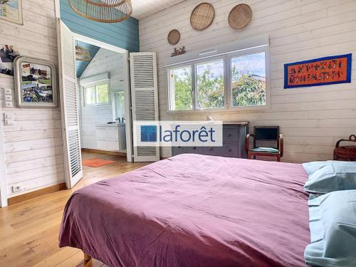 a bedroom with a large bed and a bathroom at Maison en bois avec piscine à 1000 m des plages. in Guidel