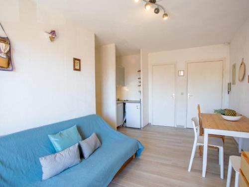 Una sala de estar con un sofá azul y una mesa. en Apartment Saint James-9 by Interhome, en Le Lavandou