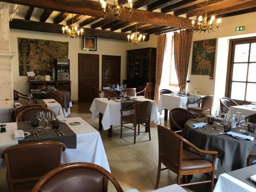 ein Restaurant mit weißen Tischen, Stühlen und Fenstern in der Unterkunft LOGIS HOTEL - Le Relais Saint Vincent in Ligny-le-Châtel