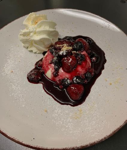 a chocolate dessert with berries and whipped cream on a plate at MOUNTAIN HOTEL Osteria di MONTAGNA La Peonia Monte Generoso in Mendrisio