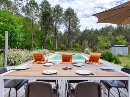 a table with chairs and an umbrella next to a pool at Villa Nico - HUT105 by Interhome in Hourtin