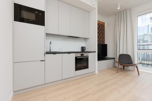 Fashionable City Center Apartment by Renters في وارسو: مطبخ مع دواليب بيضاء وكرسي