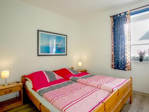 een slaapkamer met een bed met een rode en witte deken bij Apartment Kiebitzweg-2 by Interhome in Sehestedt