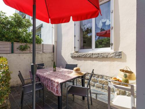 Saint-GuénoléにあるHoliday Home Ty Martelod - SGU108 by Interhomeのパティオ(赤い傘付きのテーブルと椅子付)