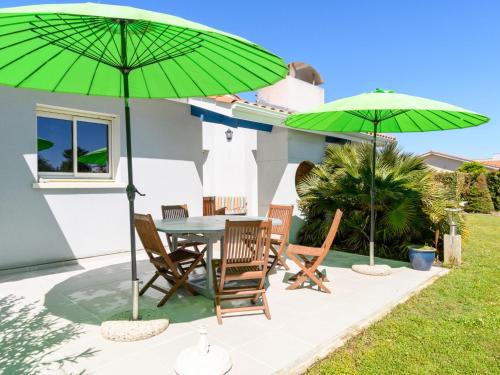 un patio avec une table et deux parasols verts dans l'établissement Holiday Home La Clairière - BPL510 by Interhome, à Enhil