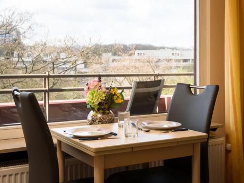 a table with chairs and a vase of flowers on a window at Apartment B609 by Interhome in Lahnstein