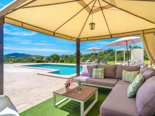 eine Terrasse mit einem Sofa und einem großen gelben Sonnenschirm in der Unterkunft Holiday Home Es Cos by Interhome in Moscari