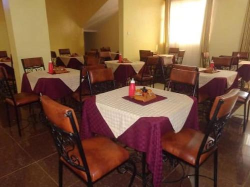 a dining room with tables and chairs with purple table cloth at Grenville Hotel in Oyugis