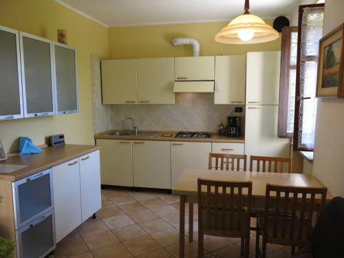 a kitchen with white cabinets and a table and chairs at Holiday Home I Grilli by Interhome in Castagnole Lanze