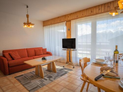 uma sala de estar com um sofá vermelho e uma mesa em Apartment Austral 204 by Interhome em Ovronnaz