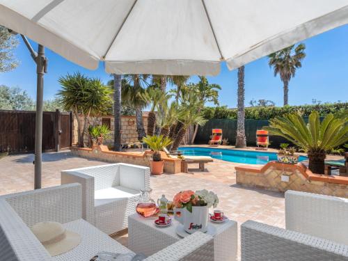 a patio with white chairs and an umbrella and a pool at Villa Albert by Interhome in San Leone