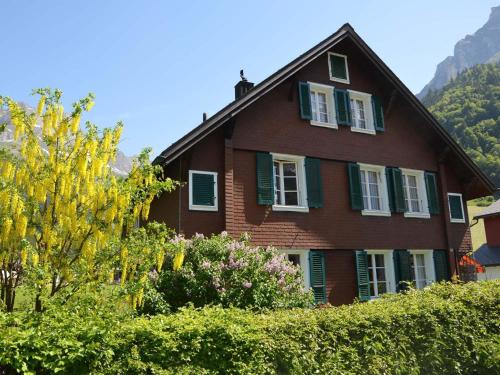 une maison brune avec des fenêtres et des buissons à volets verts dans l'établissement Apartment Hälmehois by Interhome, à Gerschnialp