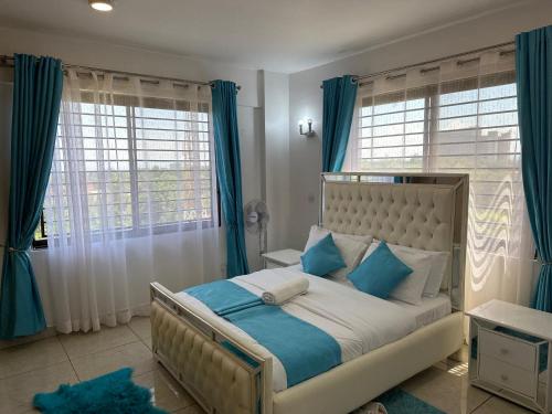 1 dormitorio con 1 cama con almohadas azules y blancas en Nyachaba Apartment, en Kisumu