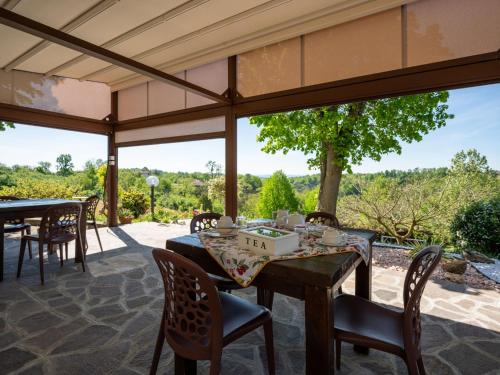 un patio al aire libre con mesas, sillas y ventanas grandes en Holiday Home Agriturismo I Tre Tigli by Interhome, en Serravalle dʼAsti