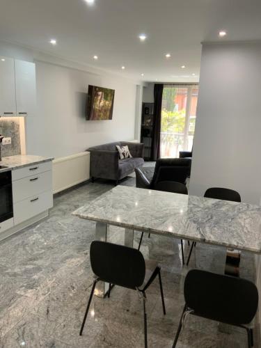 a kitchen and living room with a marble table and chairs at Jerry Apartman in Bük