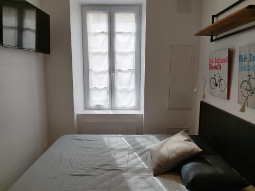 une chambre avec un grand lit avec une fenêtre dans l'établissement Le St Louis 1 Chambre aménagée avec cuisine, à La Rochelle