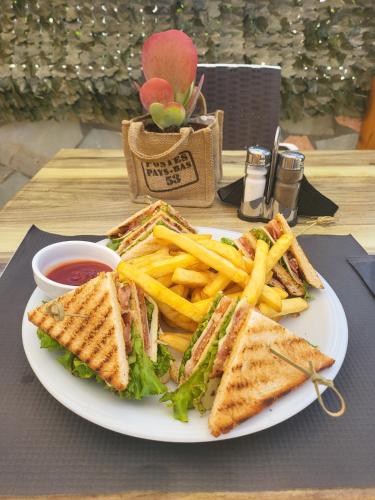 a plate with a sandwich and french fries on a table at Secret Garden Hotel in Maleme