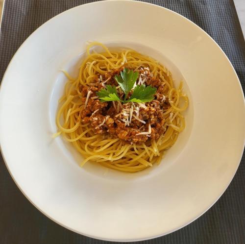 a bowl of spaghetti with meat and a garnishment at Secret Garden Hotel in Maleme