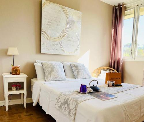 ein Schlafzimmer mit einem weißen Bett und einem Plakat an der Wand in der Unterkunft Appartement Pearl Beach in Saint-Tropez