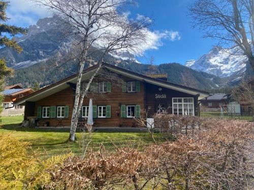 a log home with mountains in the background at Apartment Chalet Stöckli by Interhome in Kandersteg