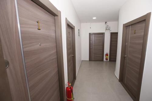 a hallway with two wooden doors and a hallway with a red extinguisher at Vurk INN Paracin in Paraćin