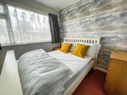 a bedroom with a bed with two yellow pillows at Beautiful Chalet With Free Wifi Nearby Hemsby Beach In Norfolk Ref 59096s in Hemsby