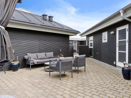 a patio with chairs and a couch and a table at Holiday Home Frethi - 350m from the sea by Interhome in Blokhus