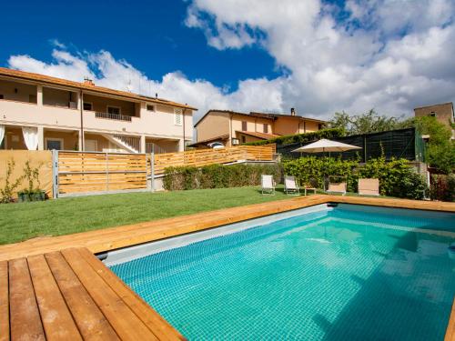 a swimming pool with a wooden deck and a house at Apartment Cinzia by Interhome in Santa Maria a Monte