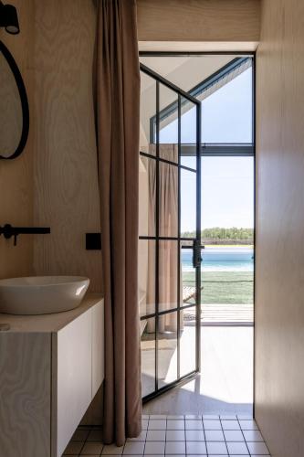 a bathroom with a sink and a glass door with a view at Vanduo Marse in Tuliejai