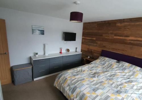 a bedroom with a bed and a tv on the wall at 5 The Fairway in Braunton