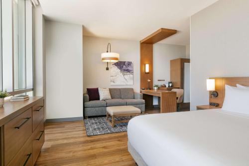 フォートワースにあるHyatt Place Fort Worth/TCUのベッドとリビングルームが備わるホテルルームです。