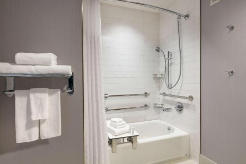 a bathroom with a tub and a shower with towels at Hyatt Place Fort Worth/TCU in Fort Worth