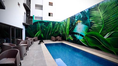 a swimming pool in a building with a mural of plants at HOTEL BELLE VUE MEKNES in Meknès