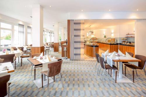a restaurant with tables and chairs and a kitchen at Vienna House Easy by Wyndham Frankfurt Airport in Kelsterbach