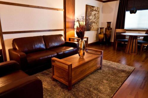 a living room with a leather couch and a coffee table at Atlantic Host Hotel, Trademark Collection by Wyndham in Bathurst