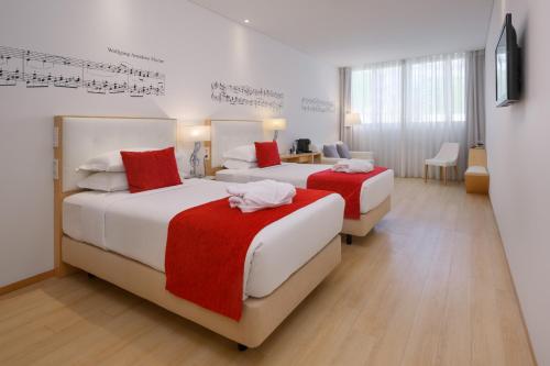 two beds in a hotel room with music on the wall at Hotel da Música in Porto