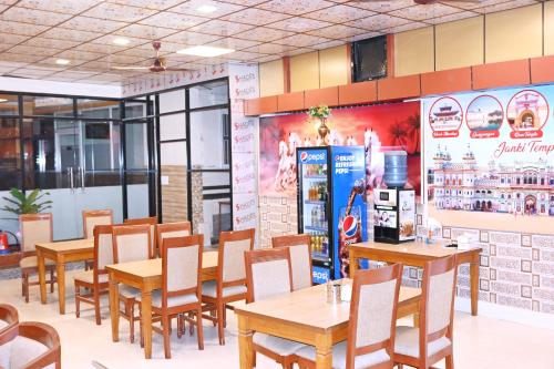 a restaurant with wooden tables and chairs and a refrigerator at HOTEL PERFECT PLAZA in Janakpur