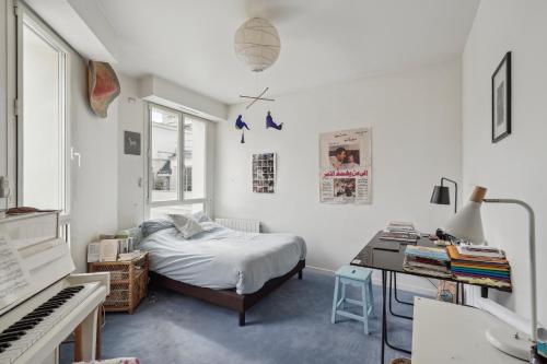 a bedroom with a bed and a desk and a piano at Charming apt for 5 people in Paris by Weekome in Paris