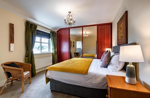 a bedroom with a large bed and a table and a chair at Foleys Ardmullen Townhouses in Kenmare