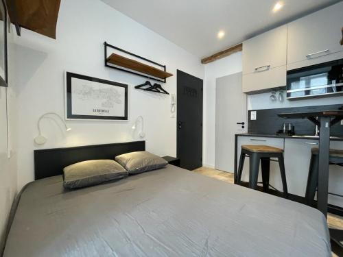 une chambre avec un grand lit et une cuisine dans l'établissement Petite chambre aménagée avec cuisine St Louis 3, à La Rochelle