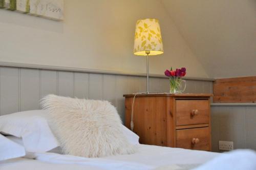 um quarto com uma cama, um candeeiro e uma cómoda em Dolmenyn em Tenby