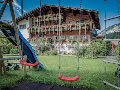a playground with swings in front of a house at Gästehaus Elfriede inklusive Sommerbergbahnticket in Haldensee