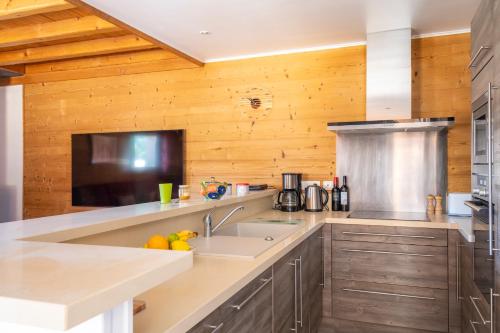 - une cuisine avec des murs en bois et un comptoir avec un évier dans l'établissement Chalet Celine, aux Gets