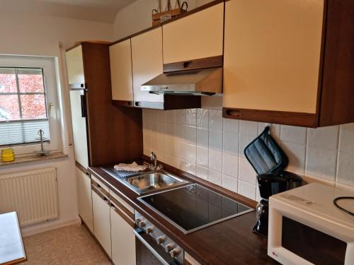 eine Küche mit Holzschränken und Spüle und einem Fenster in der Unterkunft Hausnordlicht FEWO 4 in Dornum