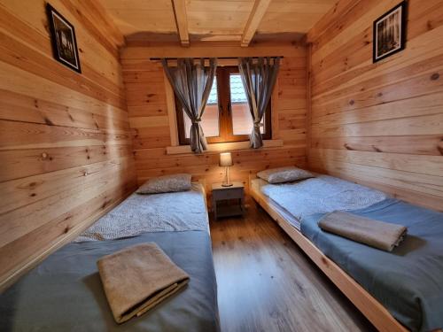 two beds in a log cabin with a window at Chatki na Kaszubach in Borsk