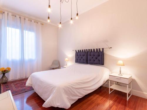 Un dormitorio con una gran cama blanca y una ventana. en Indautxu Center by Next Stop Bilbao, en Bilbao