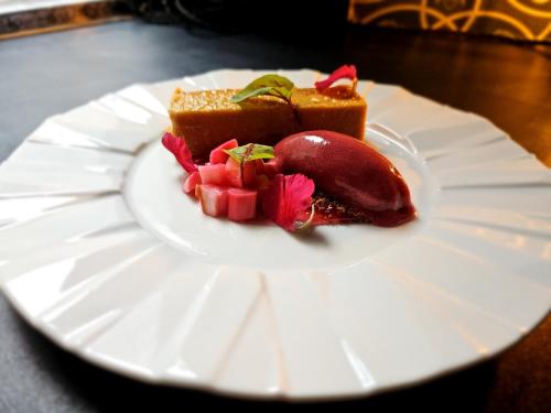 a white plate with a piece of cake and fruit at The George Hotel in Kirton in Lindsey